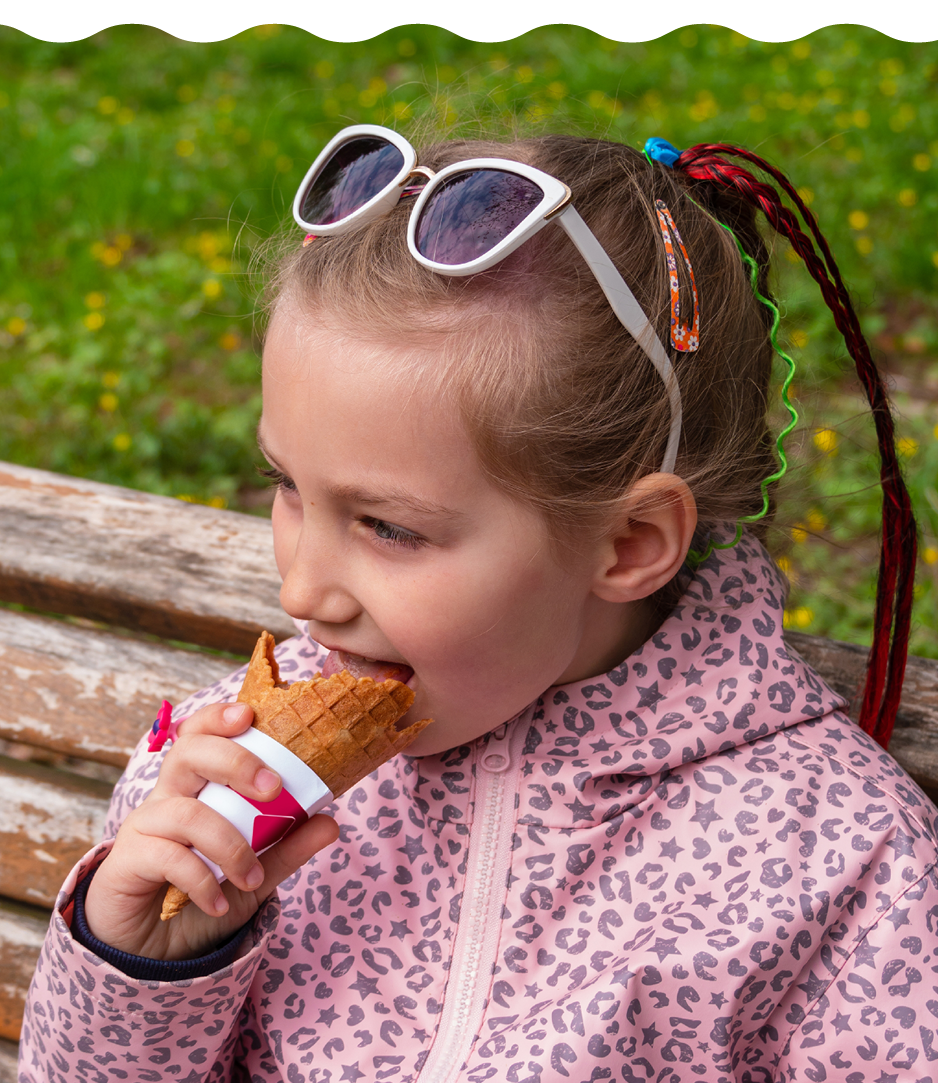 Jong meisje met zonnebril eet een ijsje